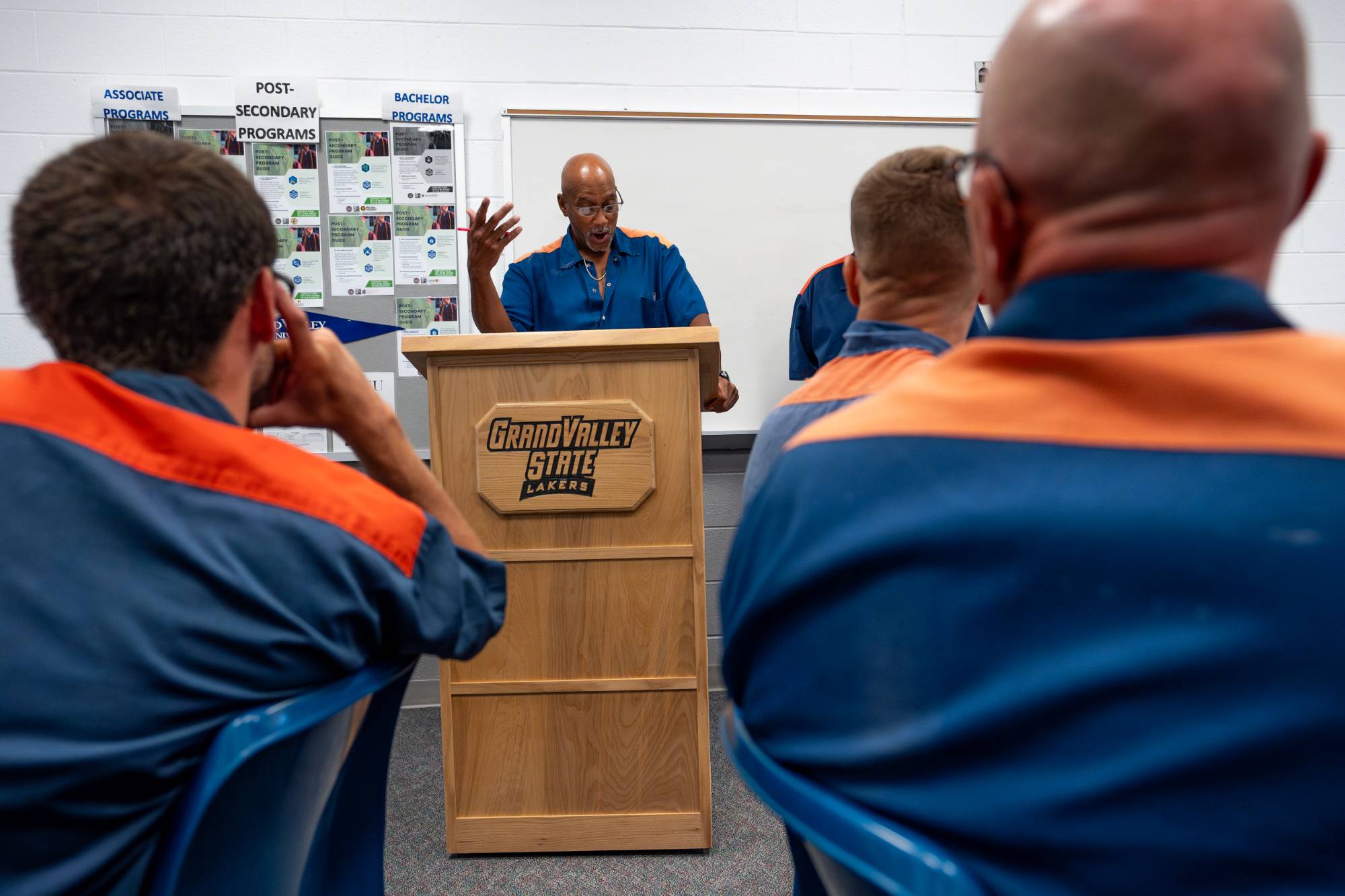 A student giving a presentation at the podium, designed and built at a woodshop in the Bellamy Creek Correctional Facility.